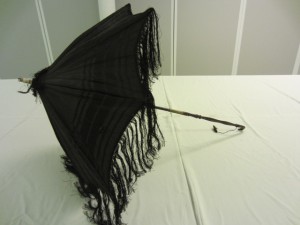 Black watered silk (moiré) decorated with satin bands woven round the edge, and trimmed with long black silk fringing. TWCMS: J166 Black watered silk (moiré) decorated with satin bands woven round the edge, and trimmed with long black silk fringing. TWCMS: J166